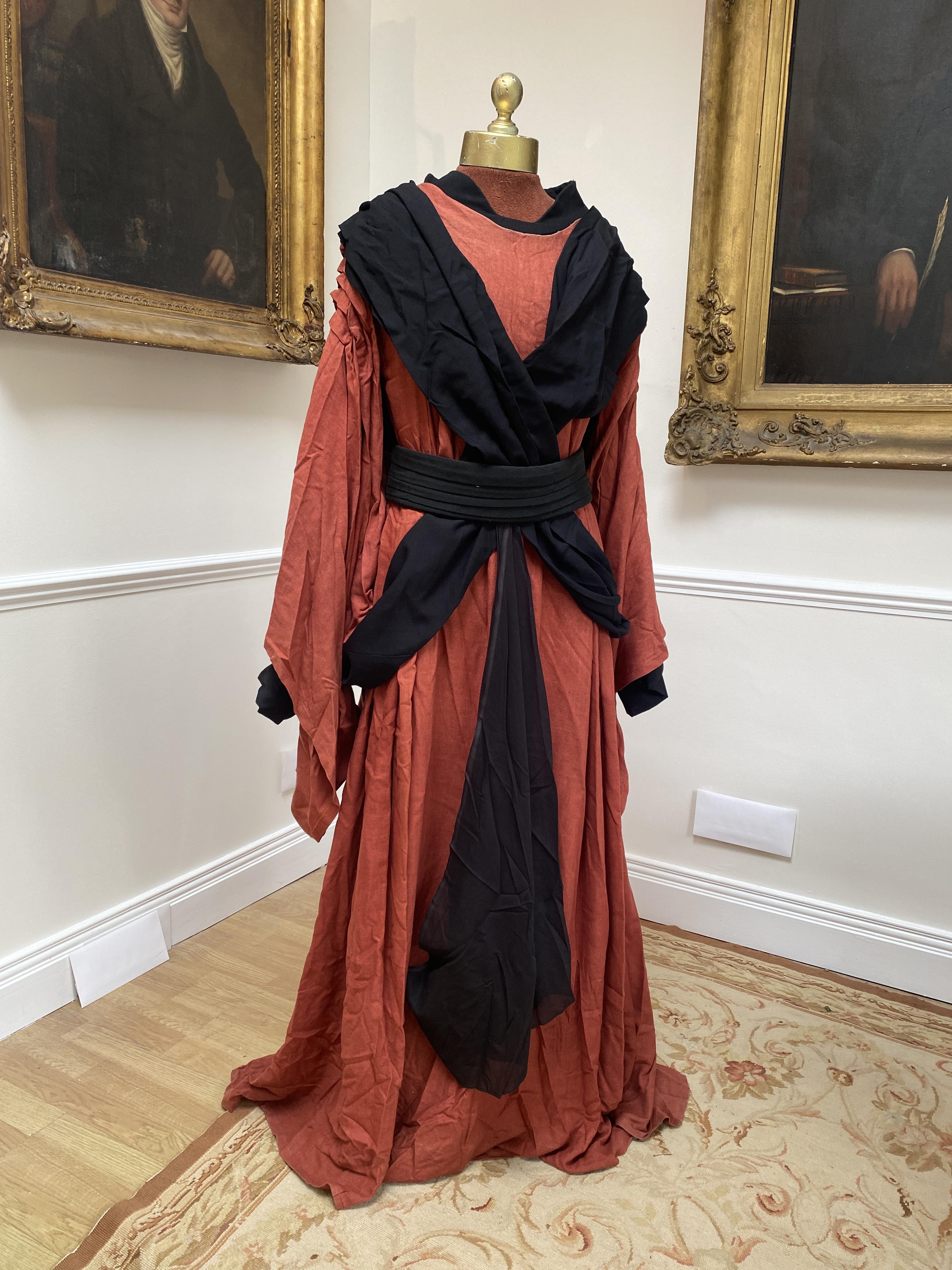 A men’s Buddhist style robe in rust linen, with black under-garment and black decorative belt, labelled Glyndebourne Festival Opera (Idomeneo)